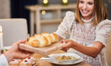woman being passed loaf of bread at dinner table